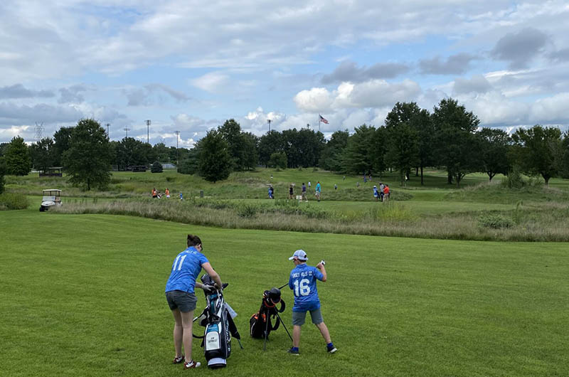 woman and junior golfers putting away their clubs